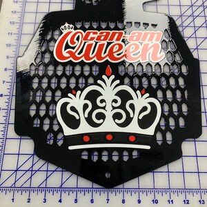 May include: Black metal radiator guard with a white and red crown graphic and the text "Can-Am Queen".