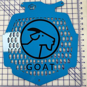May include: A blue metal radiator guard with a black goat silhouette logo and the word "GOAT" printed below. The guard has a honeycomb pattern.