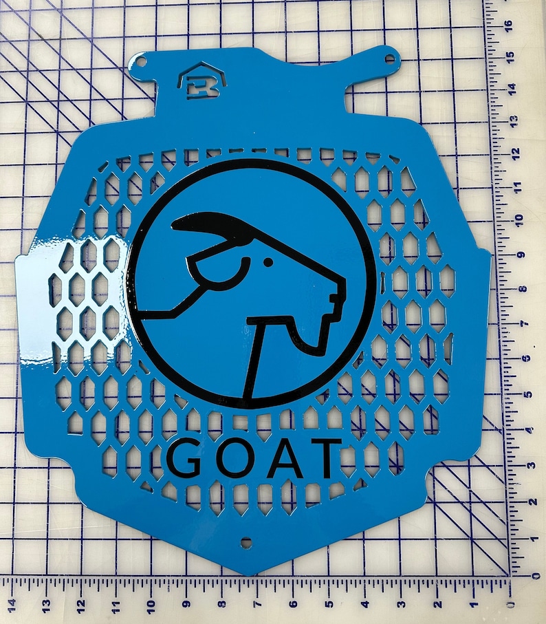 May include: A blue metal radiator guard with a black goat silhouette logo and the word "GOAT" printed below. The guard has a honeycomb pattern.