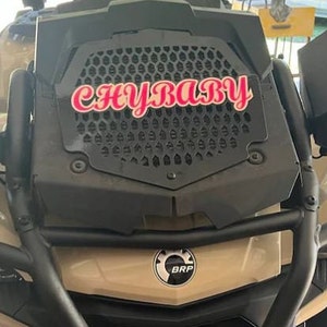 K&ouml;nnte beinhalten: Ein beiges Gel&auml;ndewagen mit einem schwarzen K&uuml;hlergrill und einem rosa-wei&szlig;en Aufkleber mit der Aufschrift "CHYBABY".