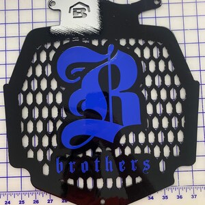 May include: Black metal radiator grille with a blue 'R' and the word 'brothers' in a stylised font.