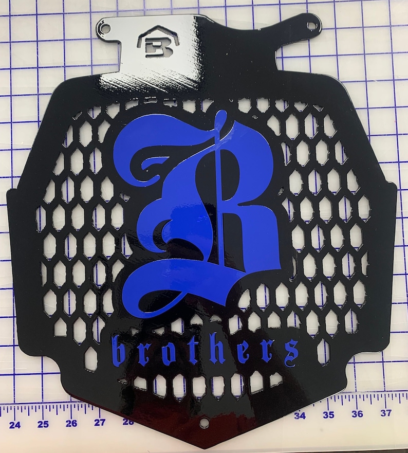 May include: Black metal radiator grille with a blue 'R' and the word 'brothers' in a stylised font.