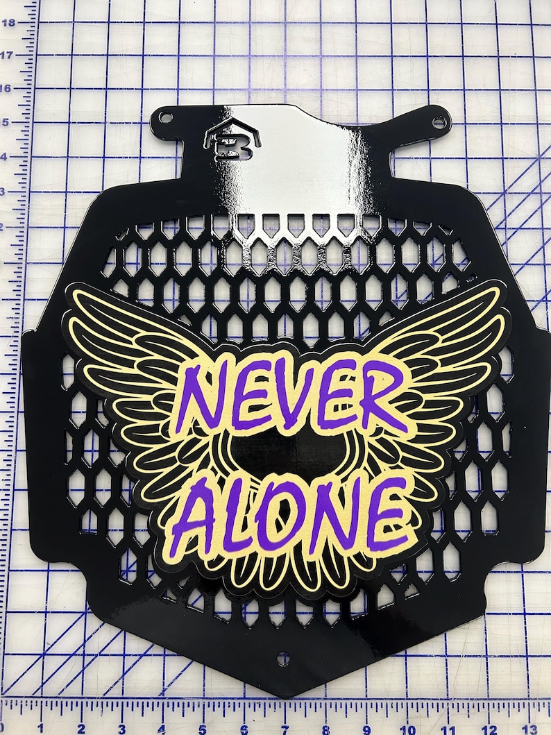 May include: Black metal grille with a yellow and purple graphic of wings and the words "NEVER ALONE".