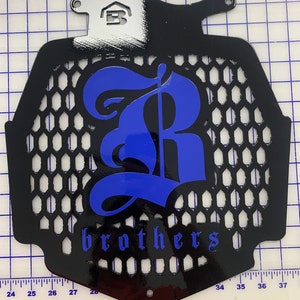 K&ouml;nnte beinhalten: Schwarzer K&uuml;hlergrill aus Metall mit einem blauen 'R' und dem Wort 'brothers' in blauen Buchstaben.