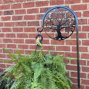 May include: Black metal tree of life silhouette with a hanging hook and a fern plant in a pot. The text "with or without redbird CHOOSE YOUR DISPLAY OPTION AND COLOR" is visible at the top of the image.