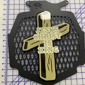 May include: A black metal grille with a gold cross and the words "JESUS CHRIST IS KING" on it.