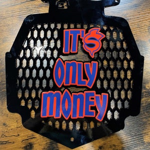 K&ouml;nnte beinhalten: Schwarzer Metallgrill mit einer roten und blauen Grafik, auf der "It's Only Money" steht.