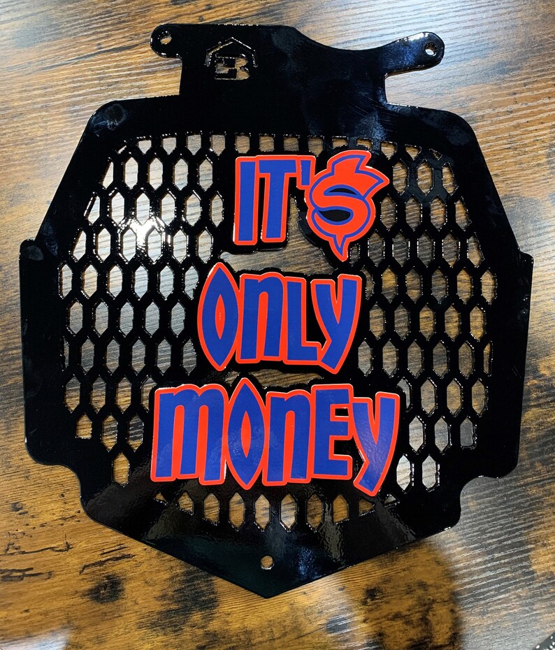 K&ouml;nnte beinhalten: Schwarzer Metallgrill mit einer roten und blauen Grafik, auf der "It's Only Money" steht.