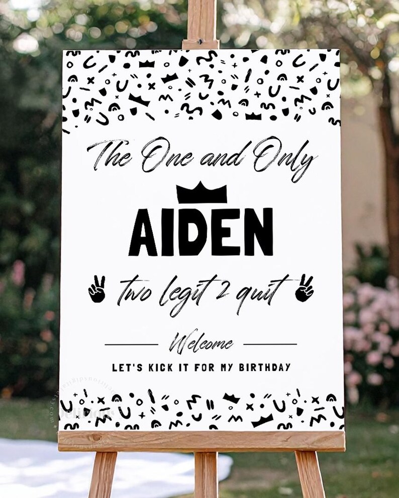 May include: A rectangular white birthday sign featuring black text and abstract shapes. The text reads: The One and Only AIDEN, two legit 2 quit, Welcome, LET'S KICK IT FOR MY BIRTHDAY. A black crown icon sits above the name, with peace sign hand icons.