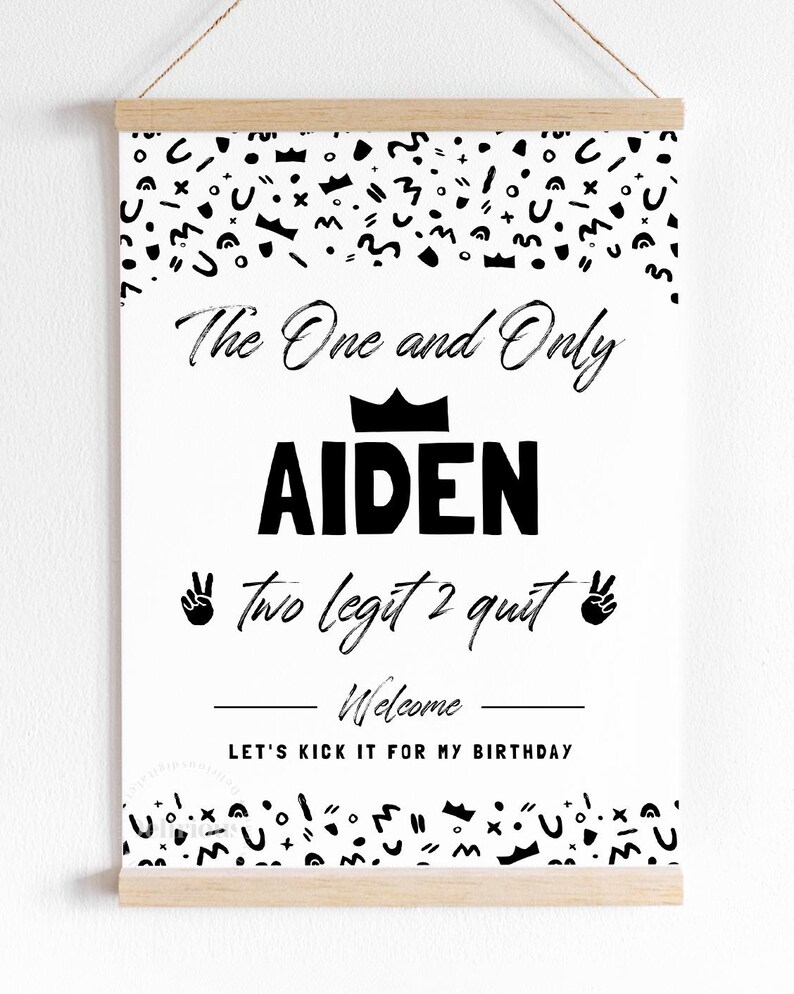 May include: A white rectangular poster with black text and abstract shapes, held by a wooden magnetic frame. The text reads: The One and Only AIDEN, two legit 2 quit, Welcome, LET'S KICK IT FOR MY BIRTHDAY, featuring crown and peace sign icons.