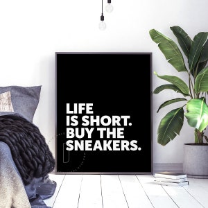 May include: Black and white poster with the text "Life is short. Buy the sneakers." on a black background.