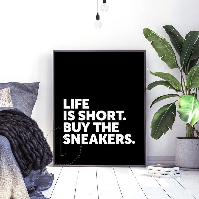 May include: Black and white poster with the text "Life is short. Buy the sneakers." on a black background.