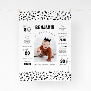 May include: A black and white printable first birthday poster with a photo of a baby boy. The poster includes the baby's name, Benjamin, and details about his first year, including his weight, height, and first word. The poster is decorated with a crown and other geometric shapes.