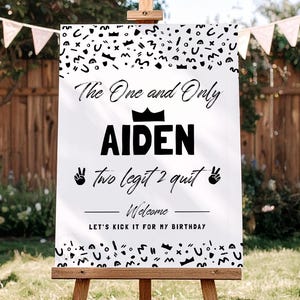 May include: A white rectangular birthday welcome sign featuring black text and abstract patterns. The sign reads: The One and Only AIDEN, two legit 2 quit, Welcome, and LET'S KICK IT FOR MY BIRTHDAY. It includes a crown icon and two peace sign hand icons.