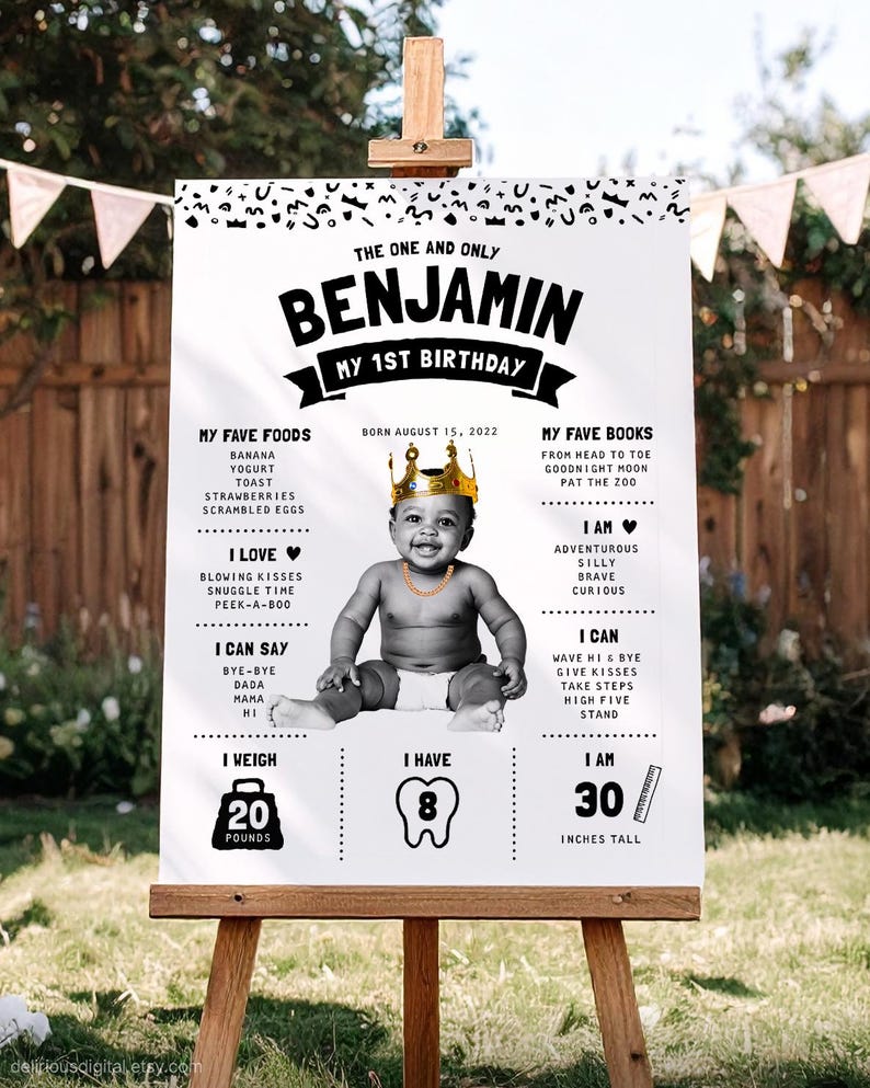 May include: A white birthday milestone sign featuring a black and white photo of a baby wearing a gold crown and chain. The text includes 'THE ONE AND ONLY BENJAMIN MY 1ST BIRTHDAY', 'BORN AUGUST 15, 2022', 'MY FAVE FOODS', 'MY FAVE BOOKS', 'I LOVE', 'I AM', 'I CAN SAY', 'I CAN', 'I WEIGH 20 POUNDS', 'I HAVE 8', and 'I AM 30 INCHES TALL'.