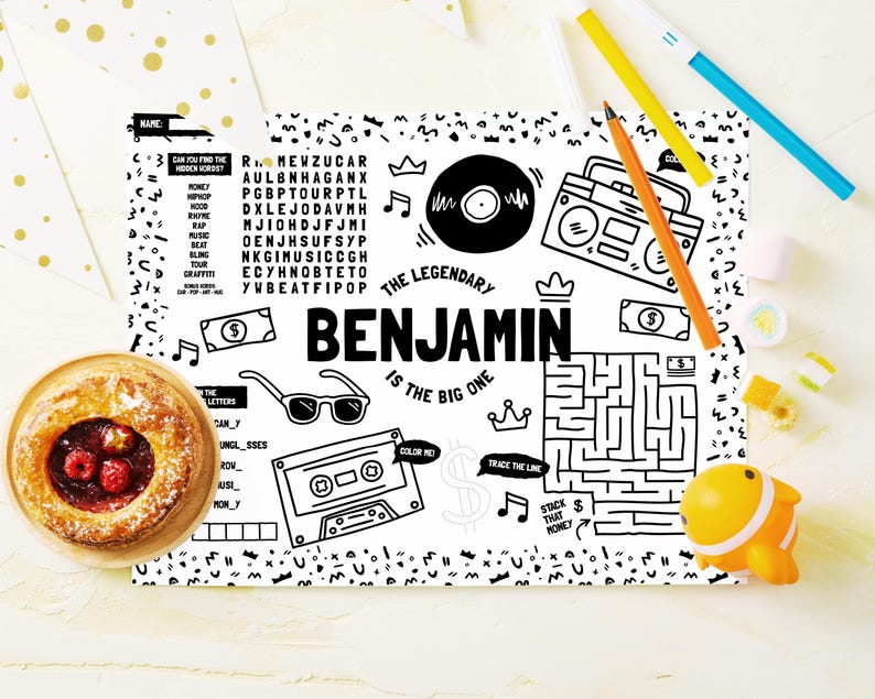May include: A black and white activity sheet featuring the text "THE LEGENDARY BENJAMIN IS THE BIG ONE" surrounded by illustrations of a vinyl record, boombox, sunglasses, cassette tape, maze, crowns, dollar bills, and a word search puzzle.