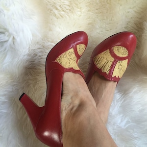 May include: A pair of red high-heeled shoes with yellow lace detailing on the vamp.
