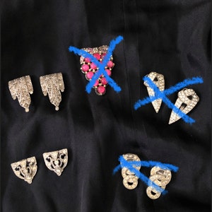 May include: A set of five vintage silver-toned brooches with rhinestones. Two brooches are shaped like a teardrop, one is a cluster of pink stones, and two are shaped like a rectangle.