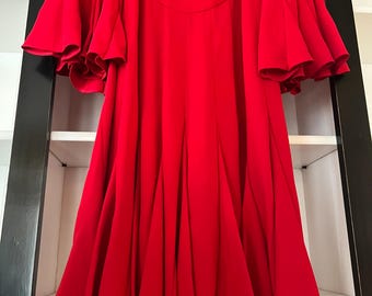Op de afbeelding: Een felrode jurk met een vloeiend silhouet. De jurk heeft een ronde halslijn en dramatische, gefranjerde mouwen. De rok wijd uit vanaf de taille, waardoor een volle, elegante vorm ontstaat. De jurk hangt voor een witte plank.