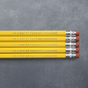 May include: Five yellow pencils with the phrase "I'm a ray of fucking sunshine." printed in silver on each pencil.