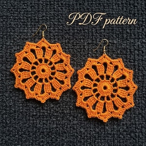 Può includere: Un paio di orecchini all'uncinetto color arancione con un motivo circolare a forma di stella e ganci in metallo dorato. Il testo "PDF pattern" è visibile nella parte superiore. Il design presenta punti complessi con un cerchio centrale.