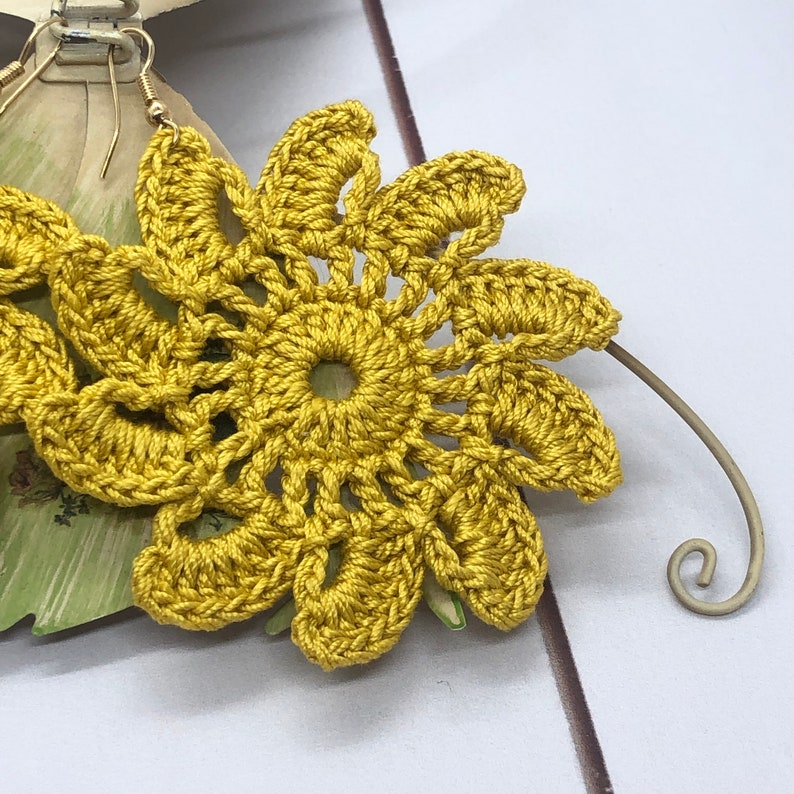 Pu&ograve; includere: Un paio di orecchini a forma di fiore di colore giallo, realizzati a uncinetto, con un gancio in filo d'oro.