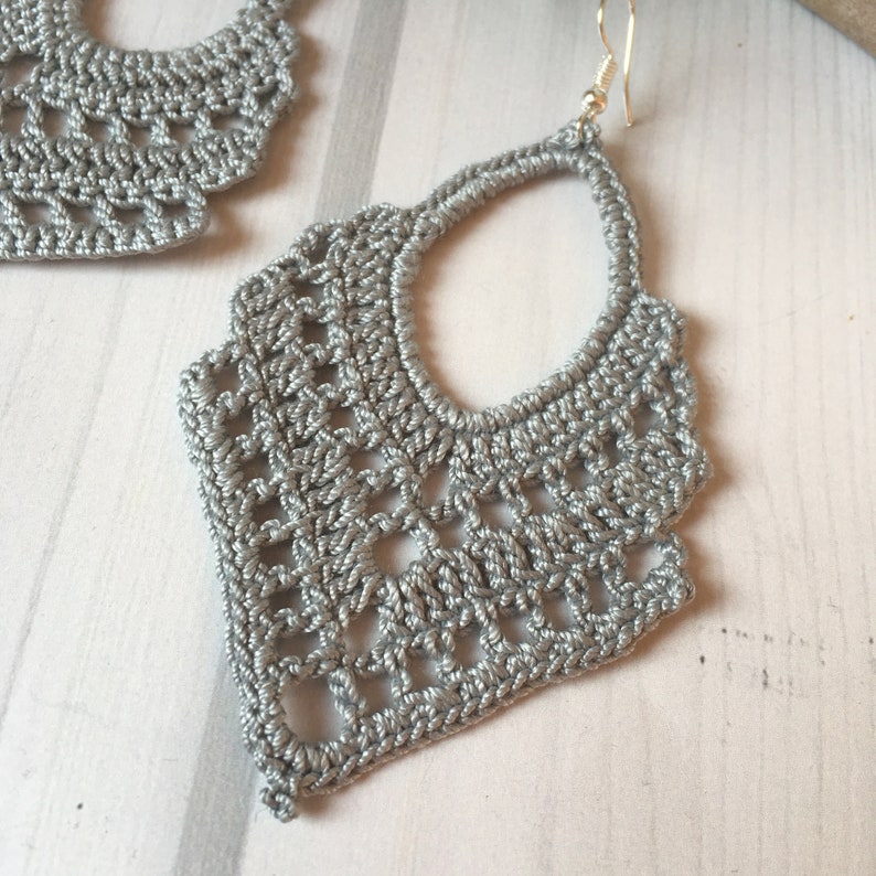 Puede incluir: Un par de pendientes de crochet plateados con un dise&ntilde;o delicado e intrincado. Los pendientes son ligeros y cuelgan de un gancho plateado.