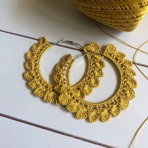 Op de afbeelding: Een paar gouden gehaakte creolen. De oorbellen zijn gemaakt met een delicaat, kantpatroon en perfect om een ​​bohemien touch aan elke outfit toe te voegen.