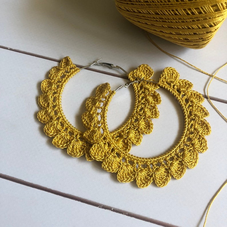 Op de afbeelding: Een paar gouden gehaakte creolen. De oorbellen zijn gemaakt met een delicaat, kantpatroon en perfect om een ​​bohemien touch aan elke outfit toe te voegen.