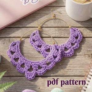 May include: A pair of handmade, lavender crochet hoop earrings with gold-colored hooks. The earrings have a scalloped edge design and are displayed on a wooden surface. The text "pdf pattern" is visible in the image.
