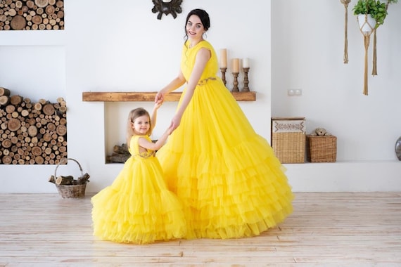 Premium Photo | A cute healthy baby girl in a yellow dress with pink tulip  flowers is sitting on a bed on white bed linen looking at the camera