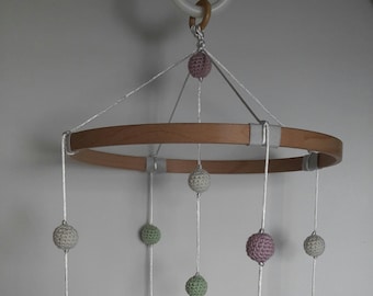 May include: A wooden baby mobile with crocheted sea creatures, including a whale, a seahorse, a turtle, a starfish, and a jellyfish. The mobile also features a variety of colored crocheted balls.