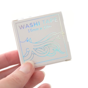 May include: A white box with a holographic finish featuring a blue and green octopus illustration. The box reads "WASHI TAPE 15mm x 10m".