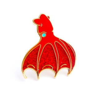 May include: A red enamel pin depicting a stylized squid or octopus. The pin features gold-coloured outlines and a small turquoise accent. The design is detailed and striking, ideal for jackets, bags, or hats.