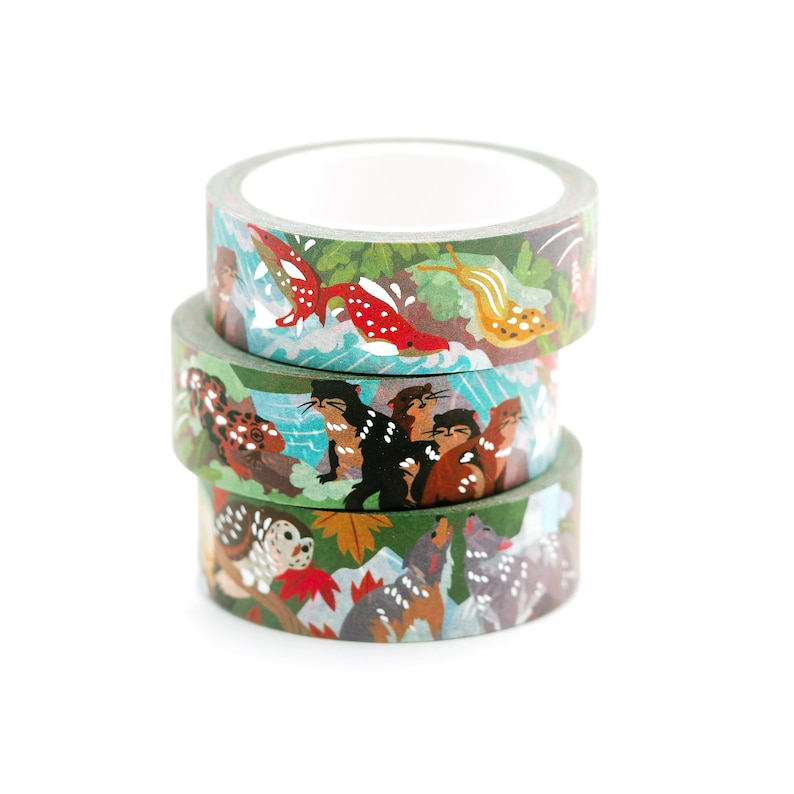 May include: Three rolls of washi tape with colorful animal and nature designs. The top roll features a red fish, a snail, and green leaves. The middle roll features a group of otters in a blue and green water scene. The bottom roll features a brown owl, a gray wolf, and red maple leaves.