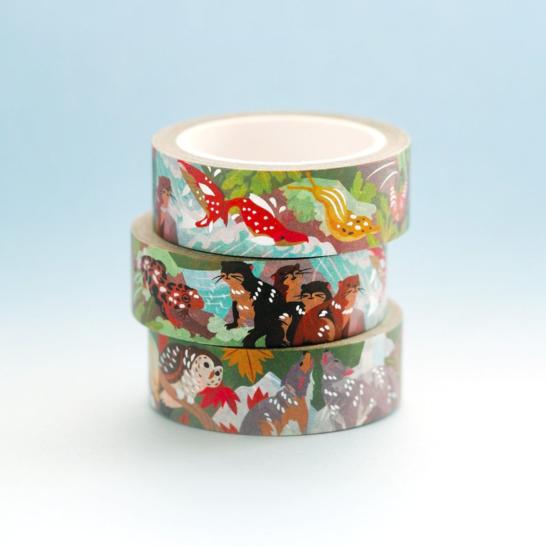 May include: Three rolls of washi tape with colorful animal and nature designs. The top roll features a red fish, the middle roll features a group of animals, and the bottom roll features a group of animals in a forest setting.