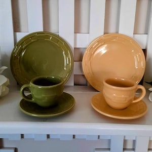 May include: Two sets of ceramic dishware, one in green and the other in a light orange. Each set includes a plate, a teacup, and a saucer. The dishware has a textured, basketweave-like design.
