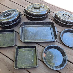 May include: A set of eight black speckled baking dishes, including a large oval dish, a smaller oval dish, a rectangular dish, a square dish, and three round pie plates.