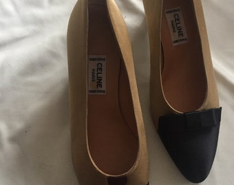 May include: A pair of gold satin pumps with black satin trim. The shoes have a pointed toe and a small heel. The shoes have a label that reads "CELINE PARIS" on the inside.