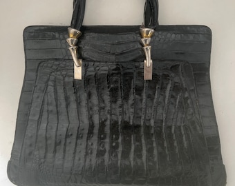 May include: A black crocodile embossed leather handbag with a braided leather handle and silver hardware.