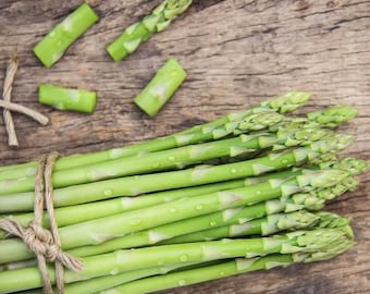 May include: A bundle of fresh green asparagus spears tied together with a piece of natural twine, accompanied by several loose, chopped asparagus segments. The vibrant green stalks feature small, tightly closed buds at the tips.