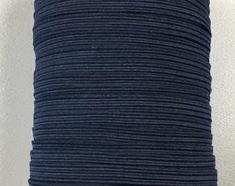 Pode incluir: Um carretel de cordão elástico azul escuro, enrolado firmemente e pronto para uso em projetos de artesanato.