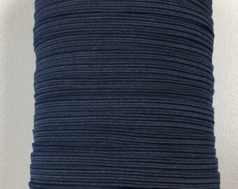 Pode incluir: Um carretel de cordão elástico azul escuro, enrolado firmemente e pronto para uso em projetos de artesanato.