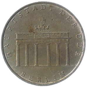 Peut inclure: Une pièce d'argent avec la Porte de Brandebourg et le texte "Hauptstadt der DDR Berlin" autour du bord.
