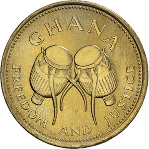 May include: A gold-colored coin featuring the word "GHANA" at the top and the words "FREEDOM AND JUSTICE" around the edge. Two drums are in the center. The coin has a textured edge.