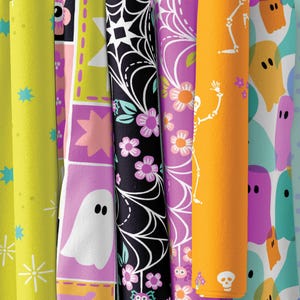Puede incluir: Una colección de rollos de papel de regalo con temática de Halloween. Los diseños incluyen fantasmas, esqueletos, telarañas y patrones florales en tonos de amarillo, morado, negro y naranja. Los rollos están dispuestos verticalmente.