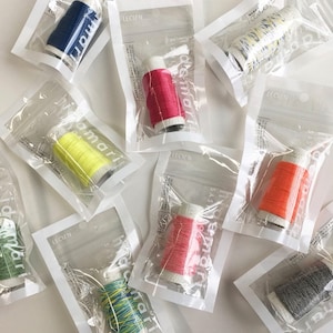 Può includere: Assortimento di bobine di filo colorate in sacchetti di plastica trasparente individuali. Ogni sacchetto ha un'etichetta con il testo "Sasayama damari" e "Lecien".
