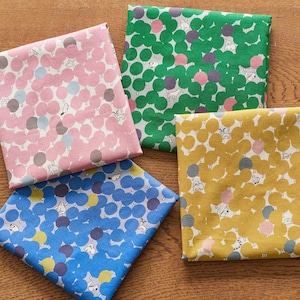 May include: Four folded fabric squares in pink, green, yellow, and blue. Each fabric features a repeating pattern of trees and small animals. The pink fabric has pink, gray, and blue trees. The green fabric has green, pink, and purple trees.