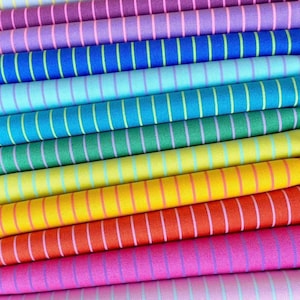 Puede incluir: Primer plano de una pila de rollos de tela colorida. La tela está rayada con líneas verticales en varios colores, incluyendo rosa, morado, azul, verde, amarillo y rojo. Las rayas son finas y espaciadas uniformemente.