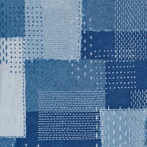 May include: A patchwork textile featuring squares of varying shades of blue denim and light blue fabric. The design incorporates white stitching in various patterns, including cross stitches and straight lines, creating a textured effect.